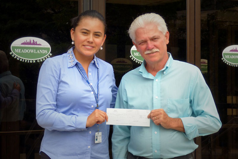 AASP/NJ President Jeff McDowell presents a check to Natalia Montoya of the Memorial Sloan Kettering Cancer Center at the Meadowlands Expositions Center, home of AASP/NJ's NORTHEAST trade show.